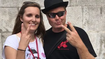 Two people posing with peace signs outdoors.
