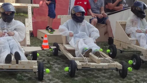 Personen mit Helmen fahren Holzkistenwagen.