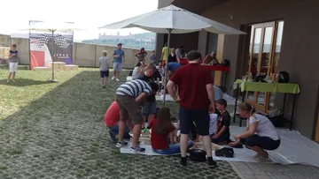 Menschen versammeln sich unter Sonnenschirmen draußen.