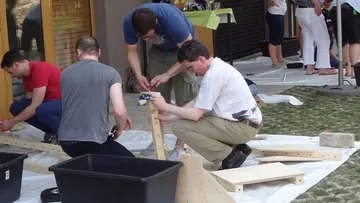 Gruppe baut Holzkonstruktionen im Freien zusammen.