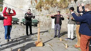 People balancing blocks with strings outdoors.