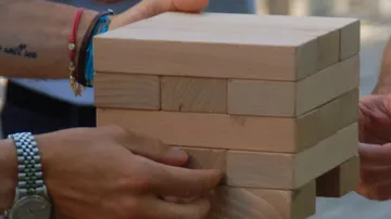 Hands holding a wooden block tower outdoors.