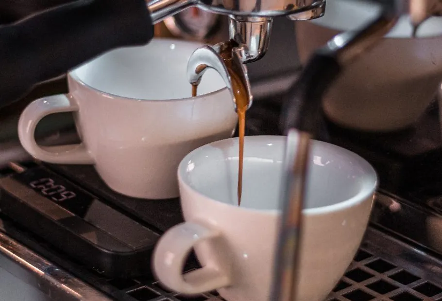 Espresso pouring into two white cups.