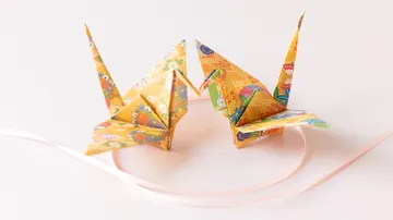 Zwei Origami-Kraniche auf weißer Fläche.