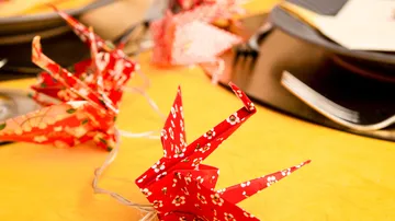 Origami-Papierkraniche auf dekoriertem Tisch.