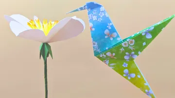 Origami-Kolibri nahe Papierblume.