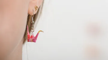 Origami crane earring on ear.