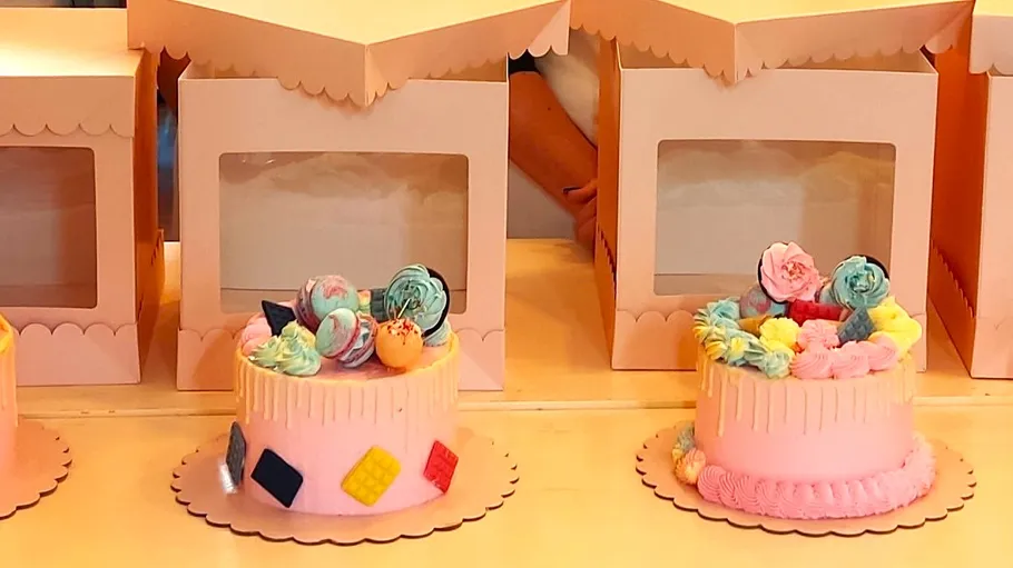 Decorative pink cakes in front of boxes.