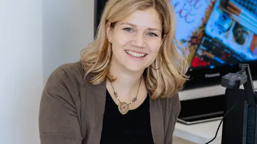 Smiling woman sitting at office desk.