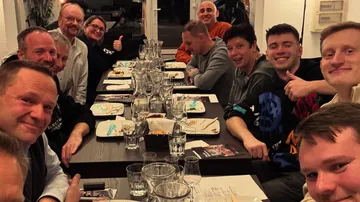 Group of people smiling around a dining table.