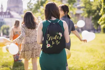 Frau mit 'Bride To Be'-Rucksack draußen.
