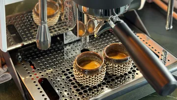 Espresso machine brewing into textured cups.
