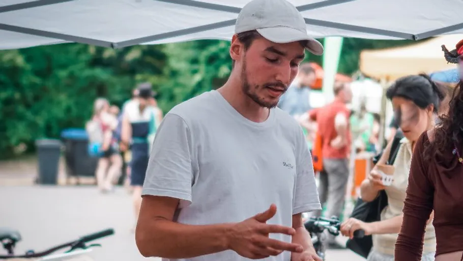 Mann im weißen Hemd spricht unter Zelt bei Veranstaltung.