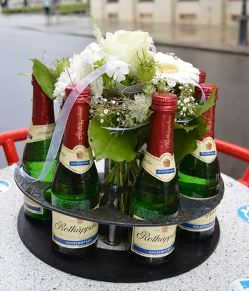 Bottles of sparkling wine with flowers outdoors.