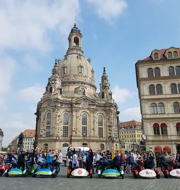 People on trikes in front of historic church.