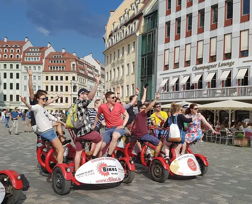 Gruppe fährt Fahrrad auf städtischem Platz, sonniger Tag.