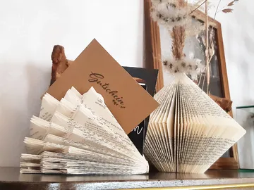Foldable book objects are on a shelf, decorative cards next to them.