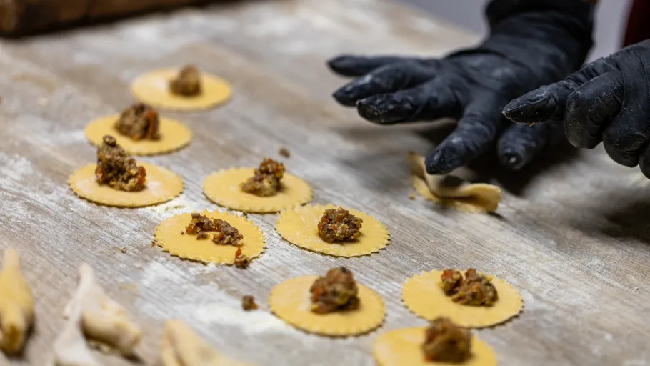Person fills pasta circles with meat filling.