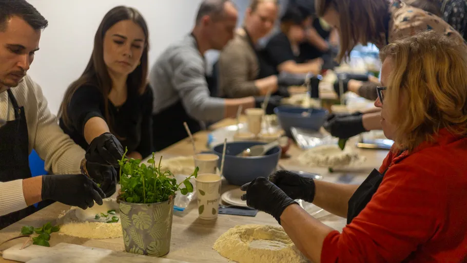 People wearing gloves baking together at table.