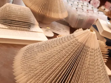 Folded book pages sit on a table in a creative space.