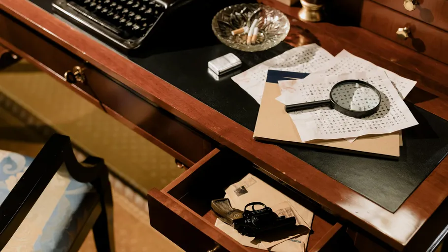 Desk with papers, magnifying glass, and typewriter.