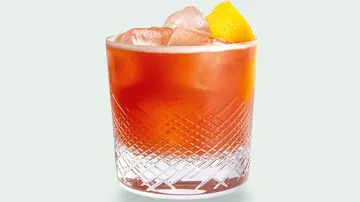 Glas mit Eis-Cocktail und Zitronengarnitur.