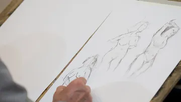 Hand sketching human figures on paper.
