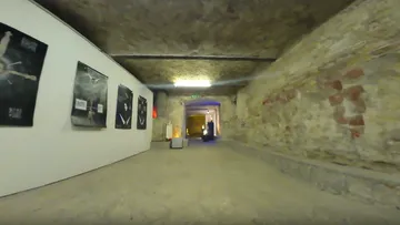Stone hallway with artwork on white walls.
