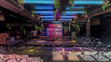 Empty comedy club with stage and colorful lights.