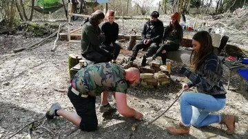 Group outdoors learning fire-starting skills.