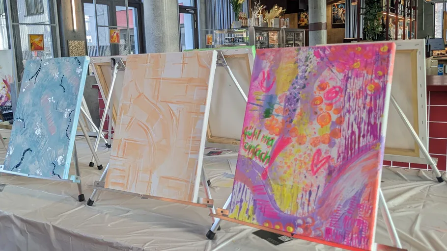 Abstract paintings on easels in an indoor space.