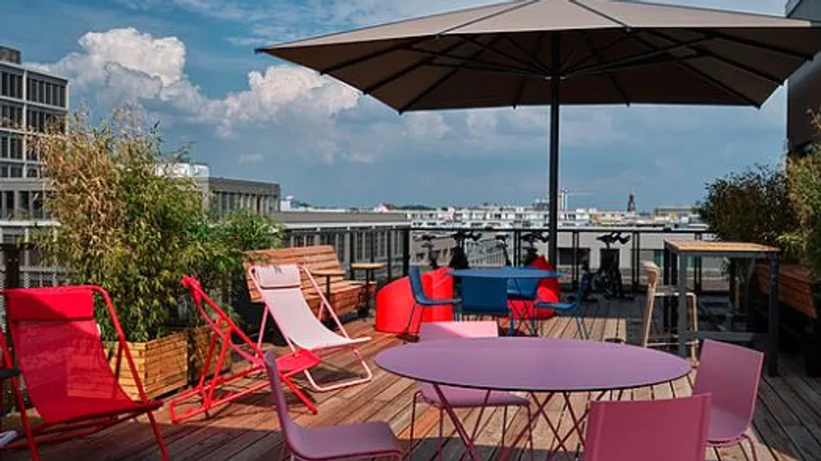 Bunte Dachterrasse mit Stühlen und Tischen.