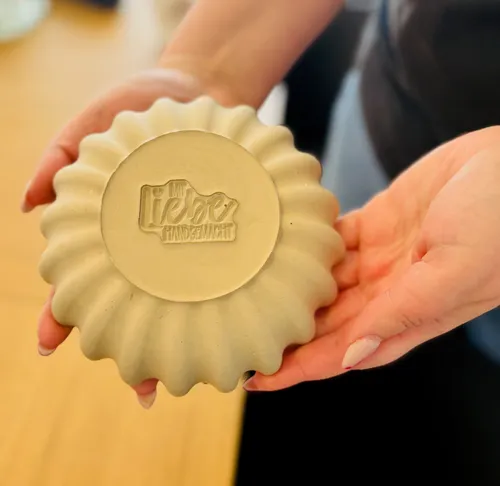 Hands holding a carved soap in a kitchen.
