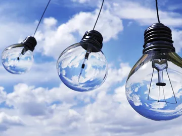 Hanging light bulbs reflect blue skies and clouds.