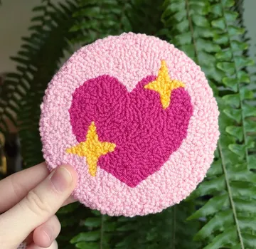 Hand hält pinkes Herz-Patch mit Sternen.