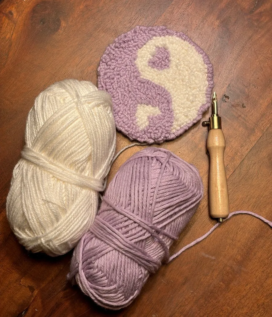 Yarn balls, punch needle, and finished circle design.