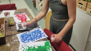Person painting colorful abstract art on paper.