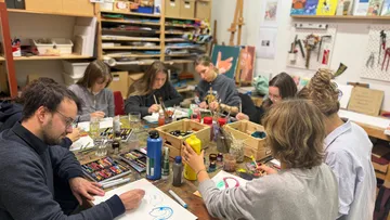 Group of people painting in an art studio.