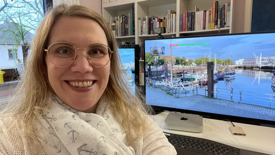 Person smiling at desk with computer screen.