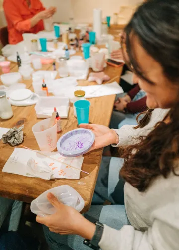 Person holding crafted item at workshop table.