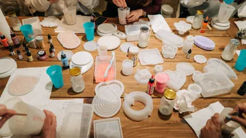 People crafting with molds and liquids on table.