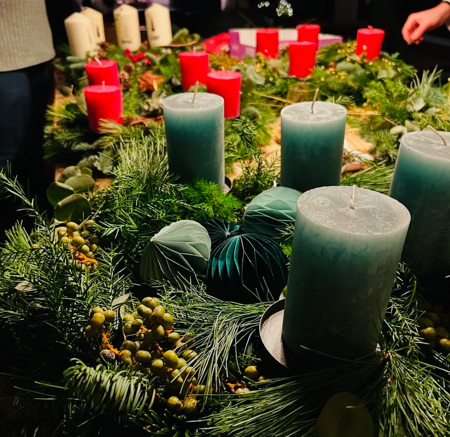 Candles on wreaths with greenery, indoors.