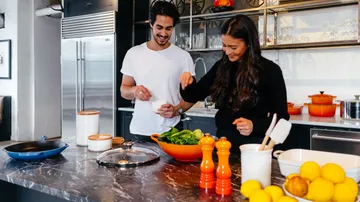 Zwei Personen kochen in moderner Küche.