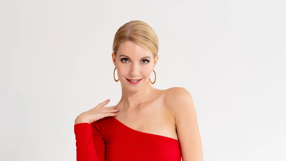 Woman in red dress posing confidently indoors.