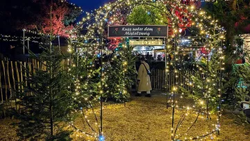 Illuminated archway with sign and decorations.