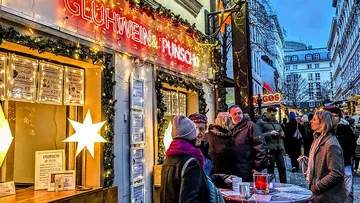 People enjoying drinks at Christmas market stall.