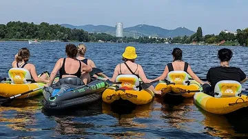 Five people in inflatable boats on lake.