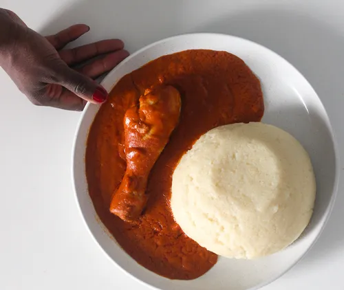 Hand serviert Fufu und Huhn in Sauce.