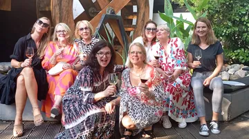Gruppe von Frauen genießt Wein im Freien.