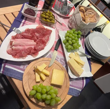 Käse, Fleisch, Trauben und Oliven auf einem Tisch.